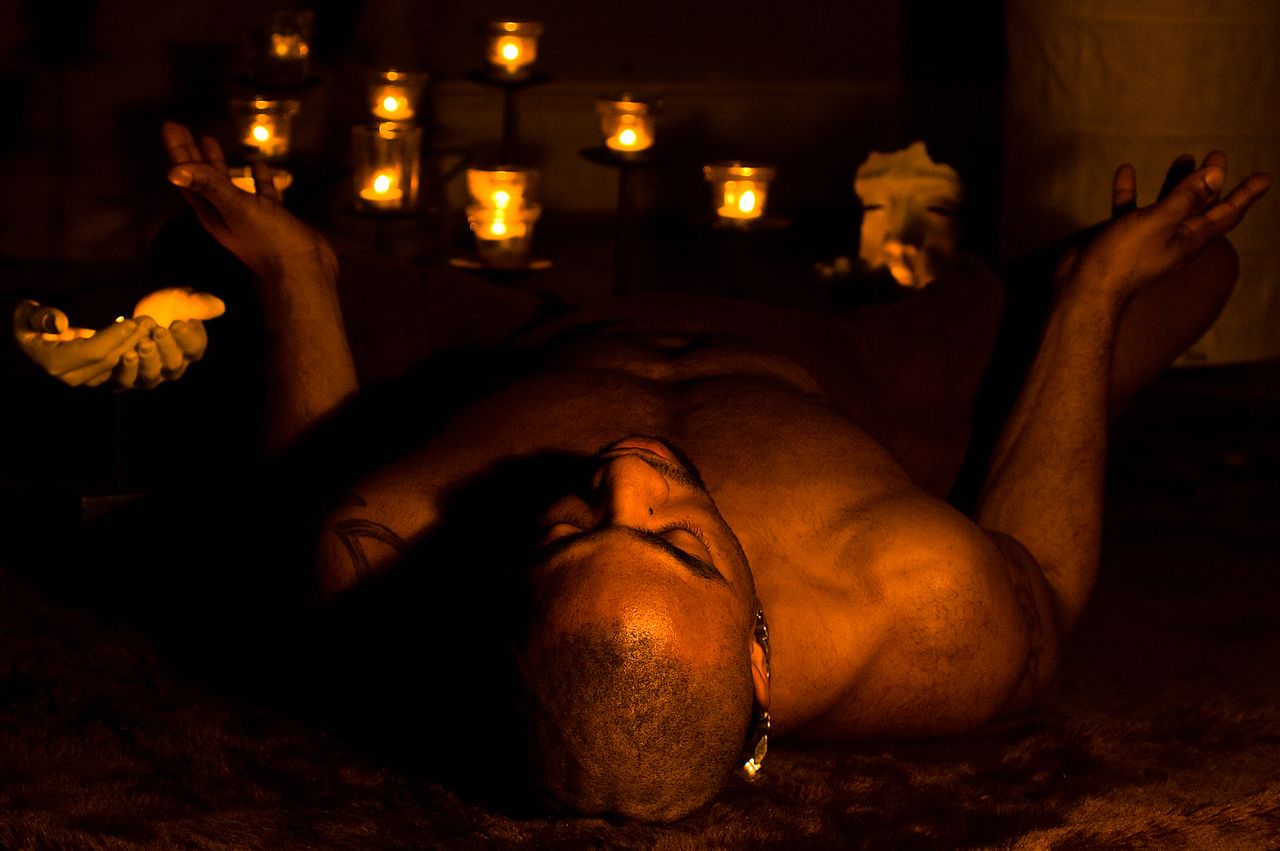 services-01 Man meditating amidst candlelight, evoking a sense of spirituality and calmness.